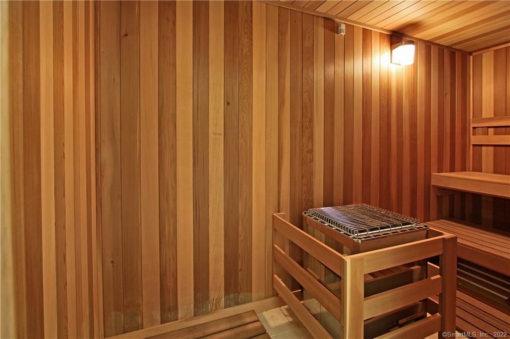Wood-paneled sauna with a central heater, protective railing, and tiered benches.