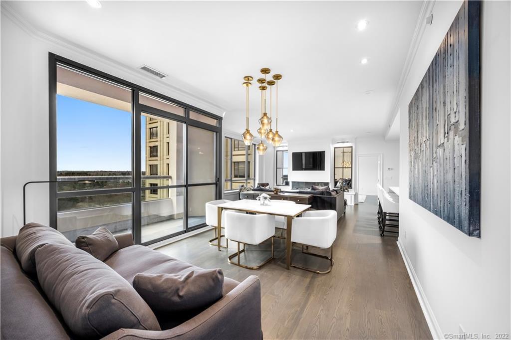 Furnished condo living and dining area with floor-to-ceiling windows and contemporary gold pendant lights.