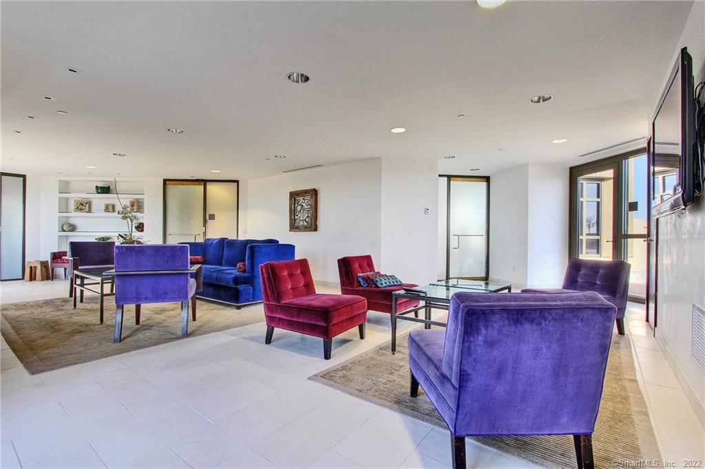 Bright condo living room with blue and purple seating, built-in shelves, and large windows.