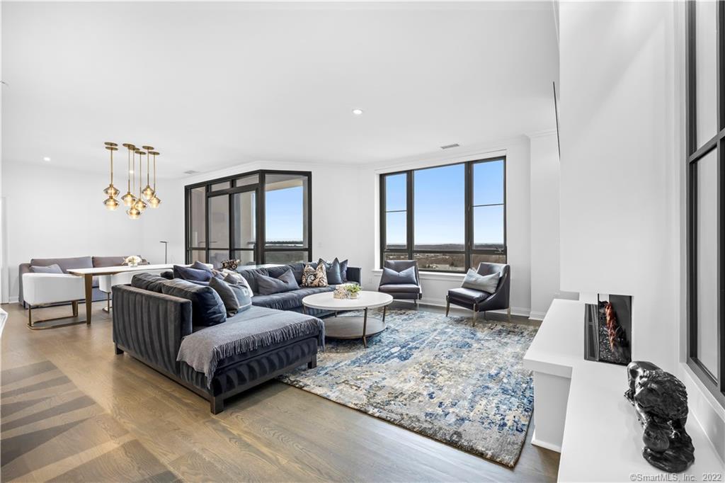 Modern condo living room with a gray sectional, blue patterned rug, and floor-to-ceiling windows.