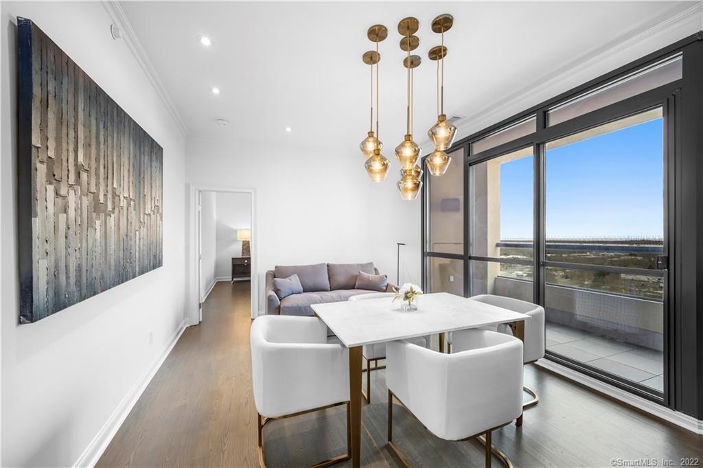 Dining area with white table and chairs beside large glass doors opening to a balcony.