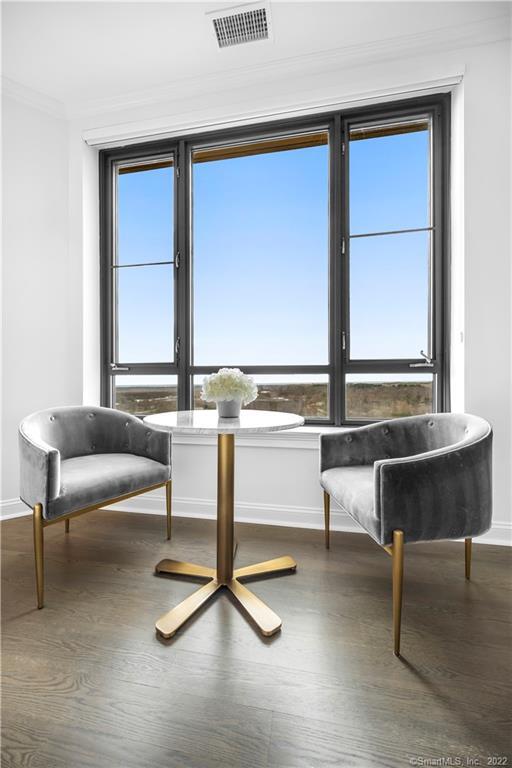 Staged sitting area with gray chairs and a round table beside a large window.