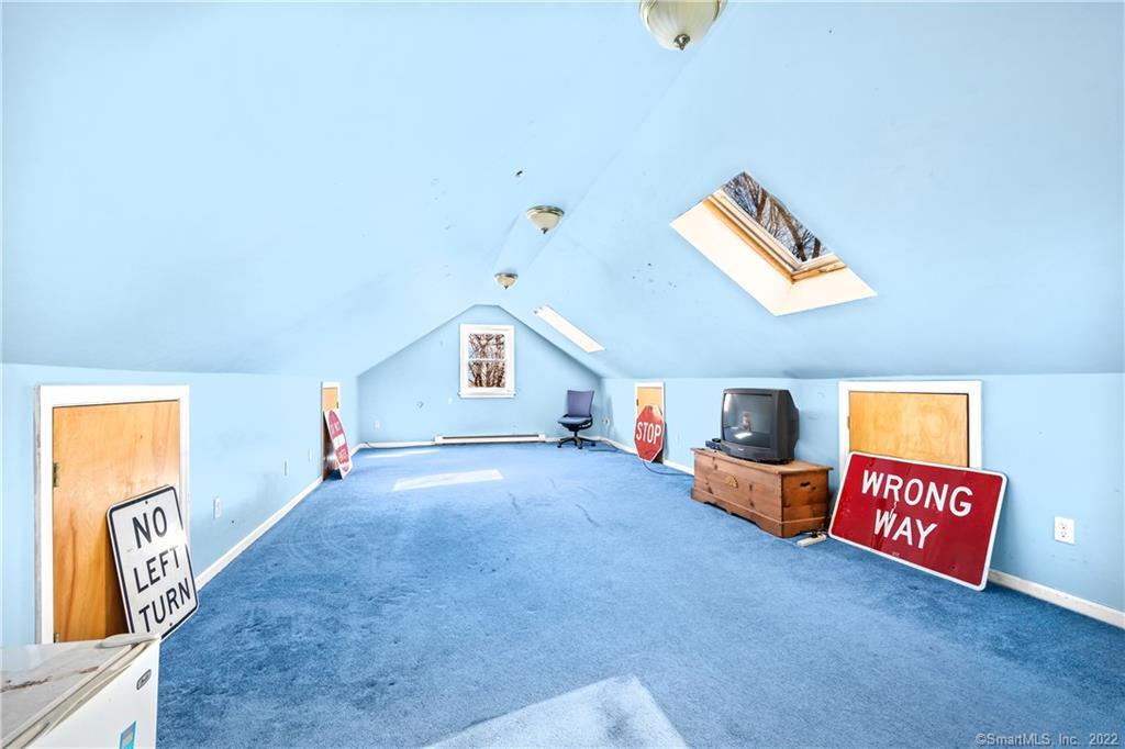 Attic bonus room with blue carpet, sloped ceiling, skylights, and traffic signs.