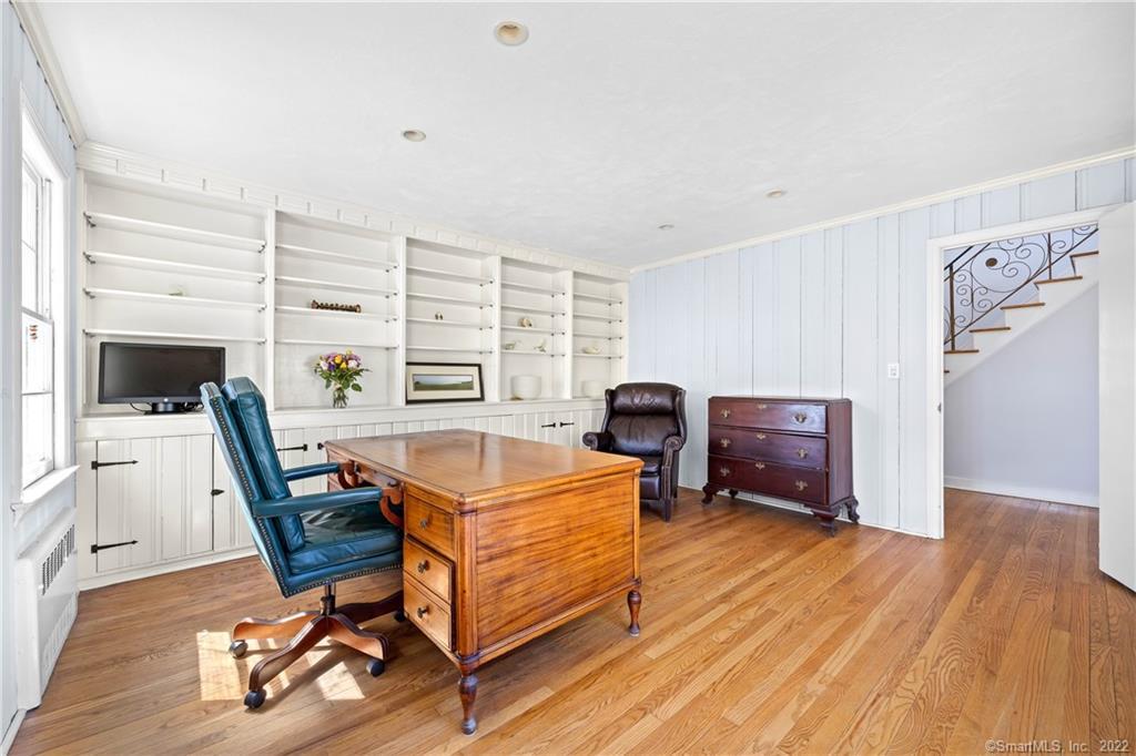 Home office with built-in white shelving, a wooden desk, and hardwood floors.