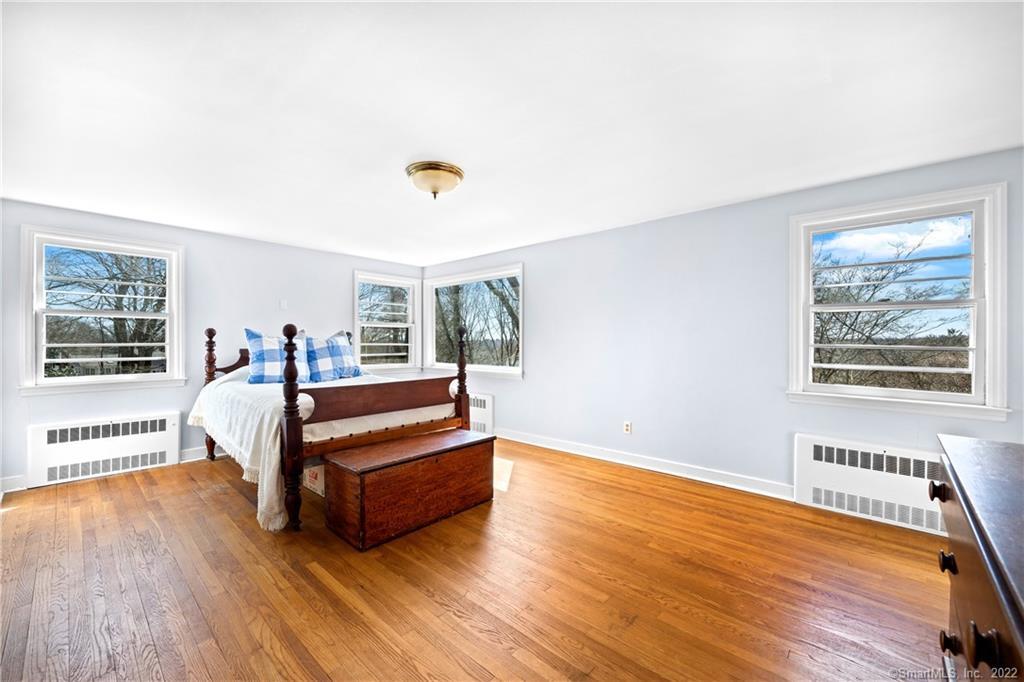 Bedroom with hardwood floors, pale blue walls, and a dark wooden bed beneath several windows.