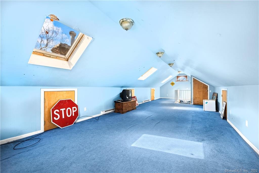Carpeted attic room with a sloped blue ceiling, skylight, and red stop sign.
