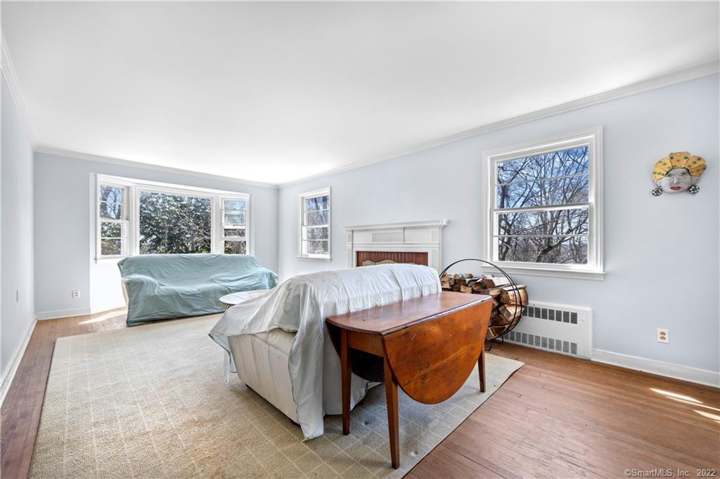 Living room with a white fireplace, large windows, and sheet-covered furniture.