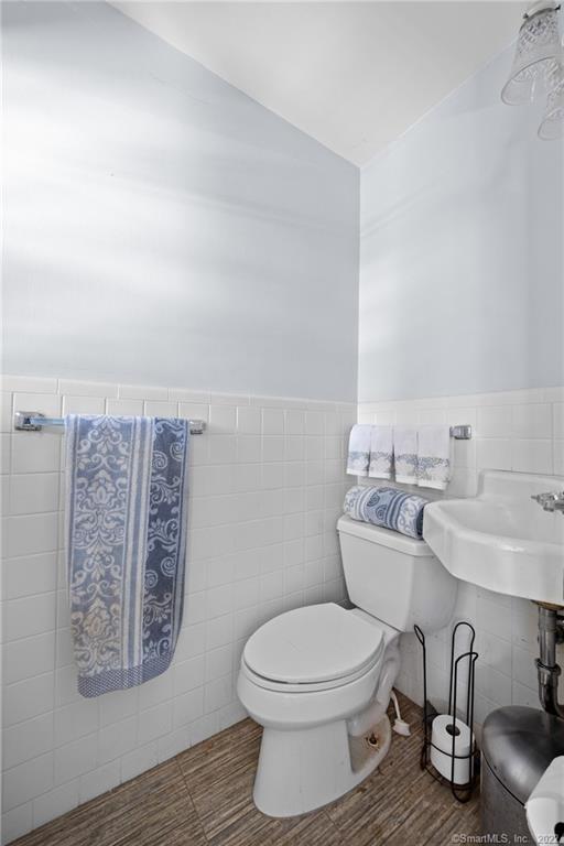 Bathroom with a wall-mounted sink, white tiled walls, and blue patterned towels.