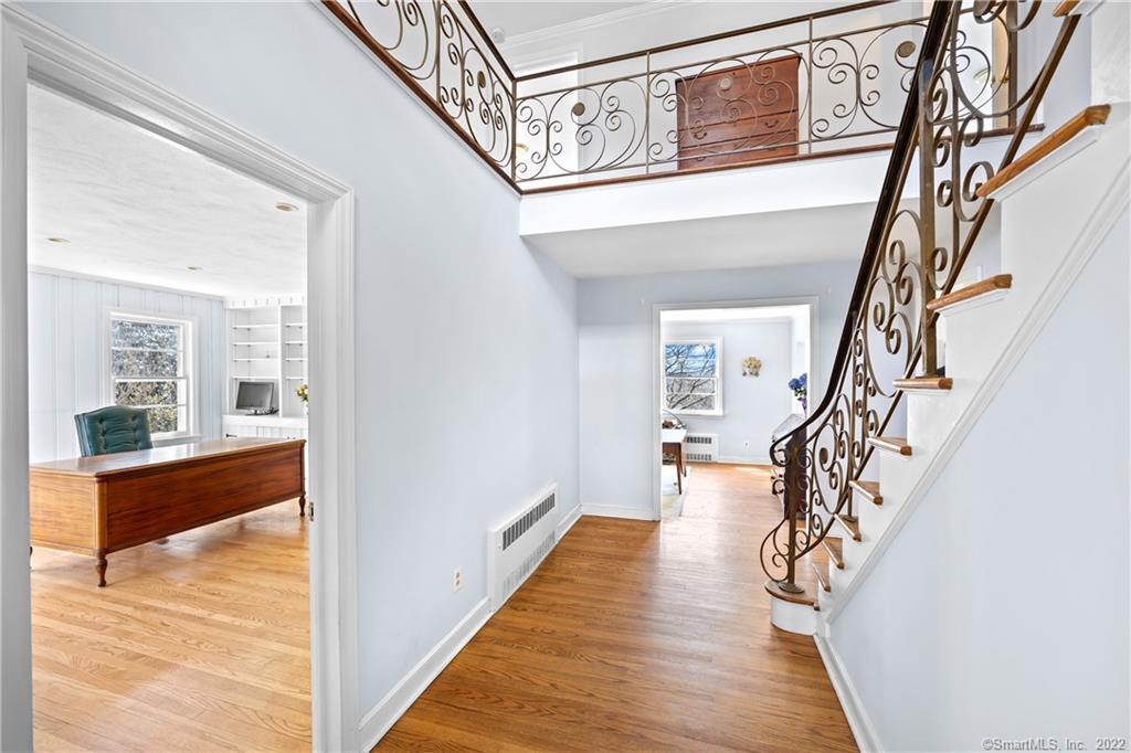 Entry hall with hardwood floors and an ornate wrought-iron staircase beside an adjoining office.