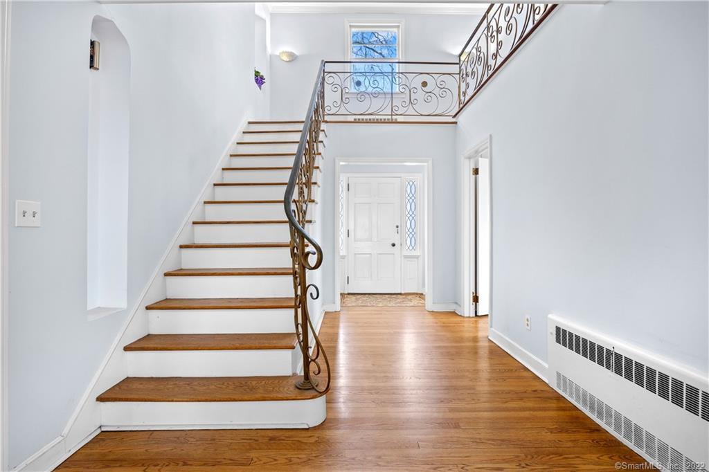 Entry foyer with a curved staircase, ornate metal railings, and hardwood floors.