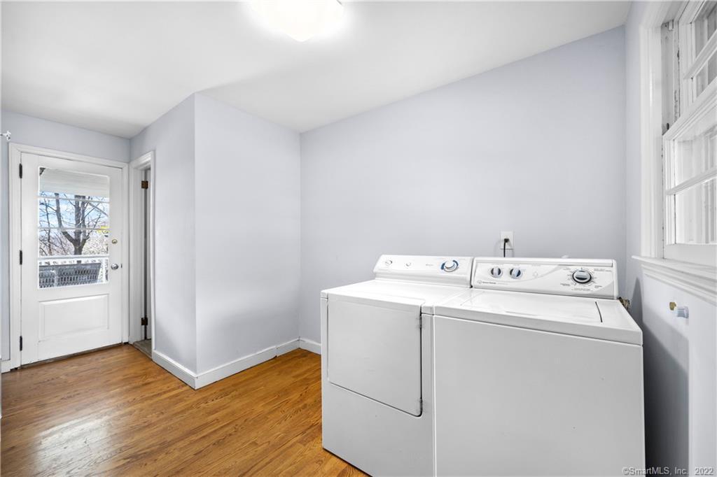 Laundry room with white washer and dryer, hardwood floors, and a glass-paneled exterior door.
