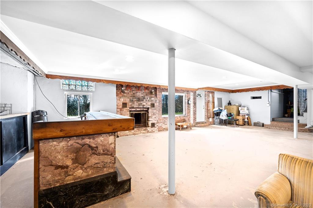 Lower-level room with a brick fireplace, stone-and-wood bar, and broad concrete floor.
