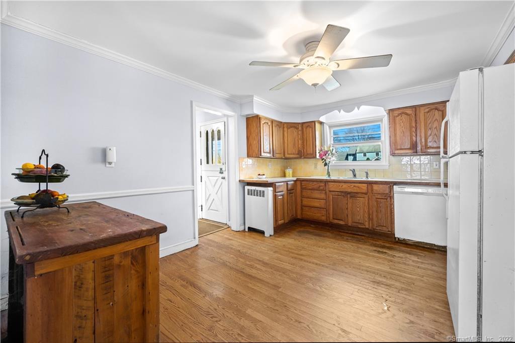 Kitchen with warm wood cabinets, hardwood floors, and a rustic table with a fruit stand.
