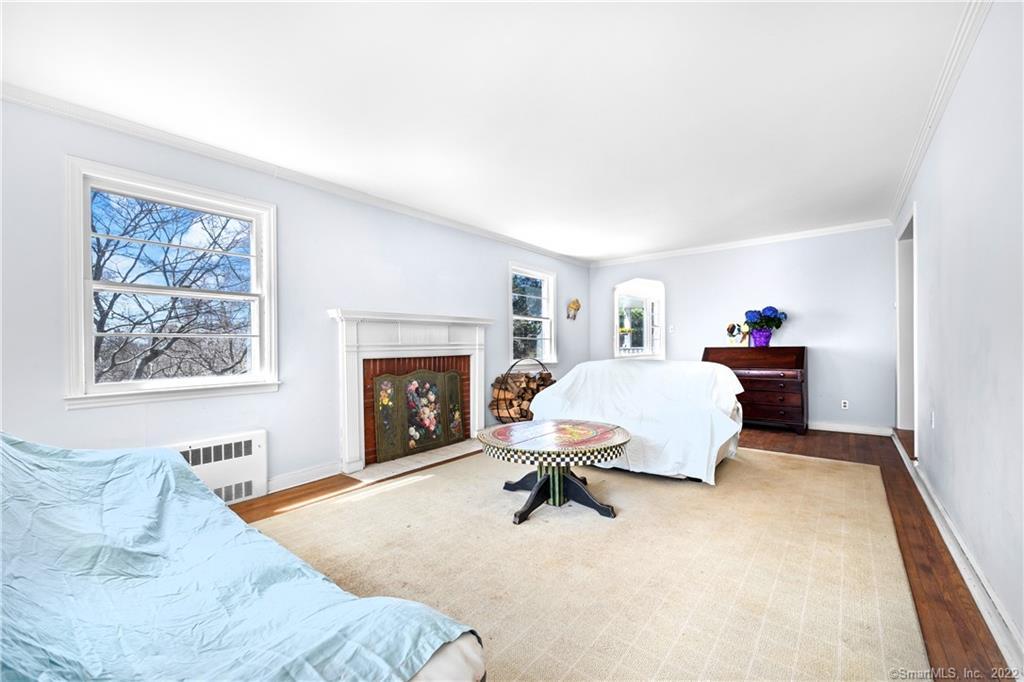 Living room with a decorative fireplace, large windows, and covered seating around a round coffee table.
