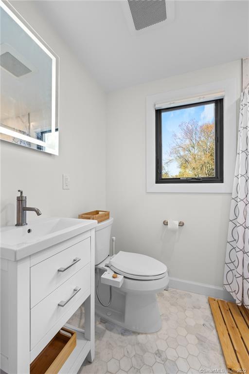 Bright white bathroom with a black-framed window, hexagonal tile floor, and modern vanity.