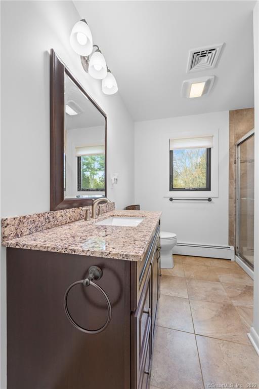 Bathroom with a dark wood vanity, granite countertop, and glass-enclosed shower.