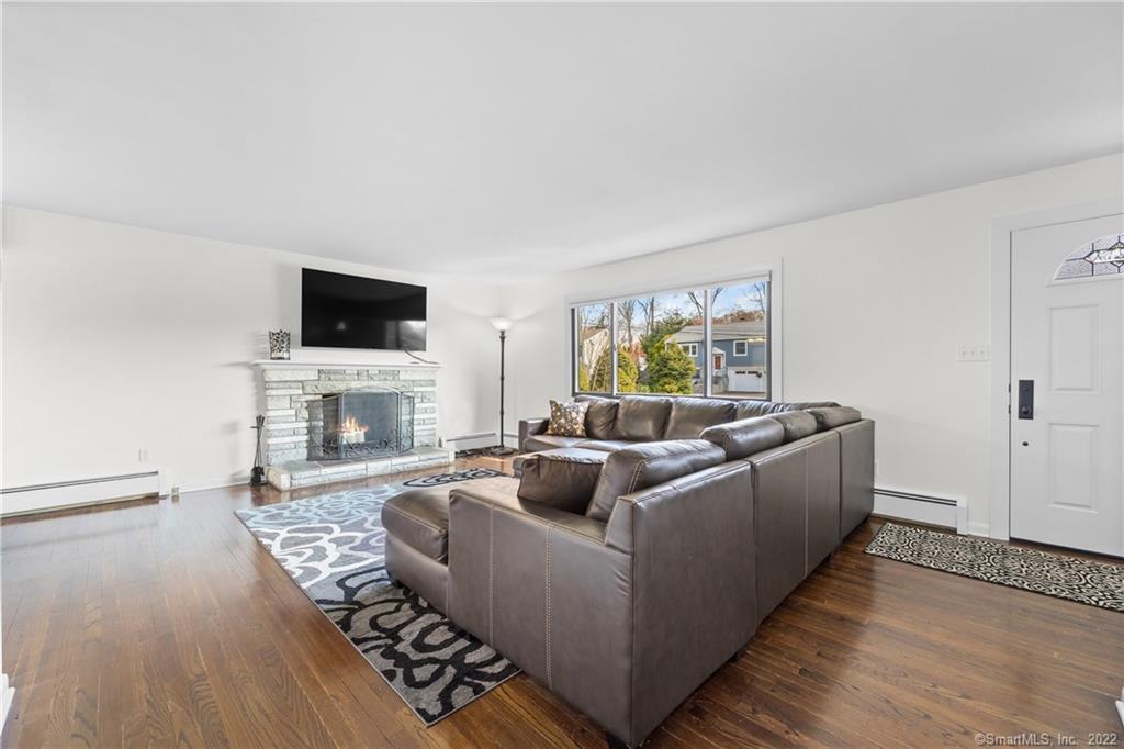 Living room with a gray sectional, patterned rug, hardwood floors, and stone fireplace.