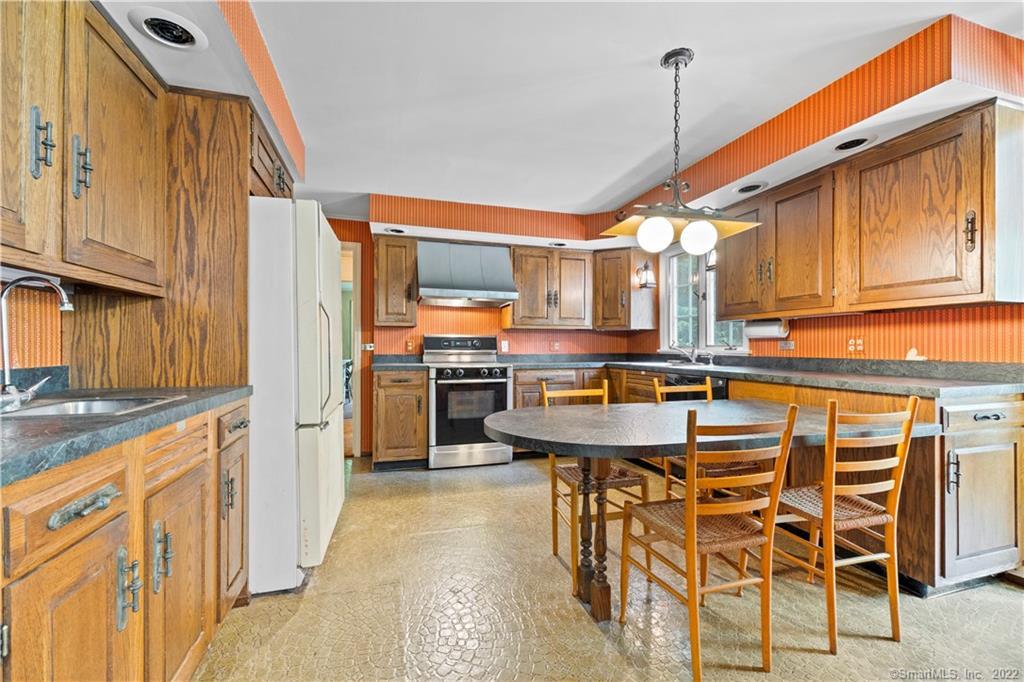 Kitchen with extensive wood cabinetry, orange striped wallpaper, and a round table with wooden chairs.