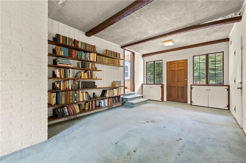 Entry room with built-in bookshelves, exposed ceiling beams, and a wooden front door.