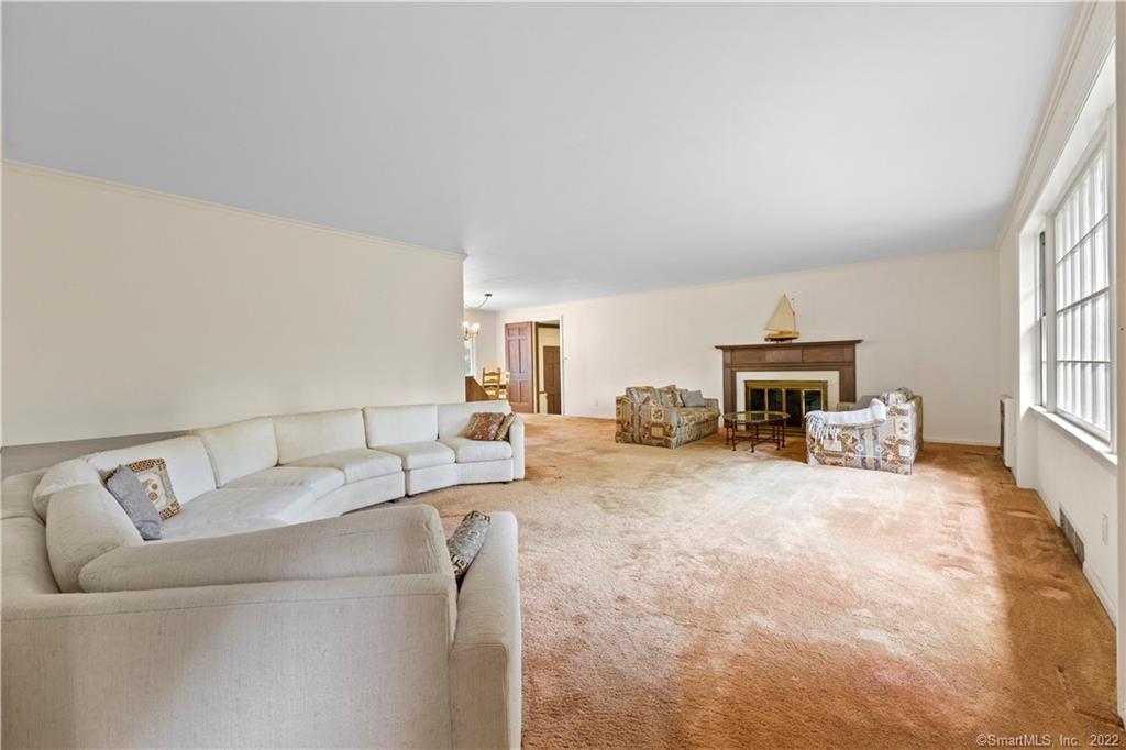 Spacious living room with a white sectional, beige carpet, fireplace, and tall windows.