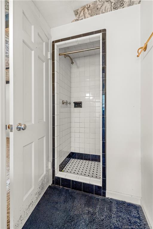 Tiled walk-in shower with dark blue trim and patterned mosaic floor.