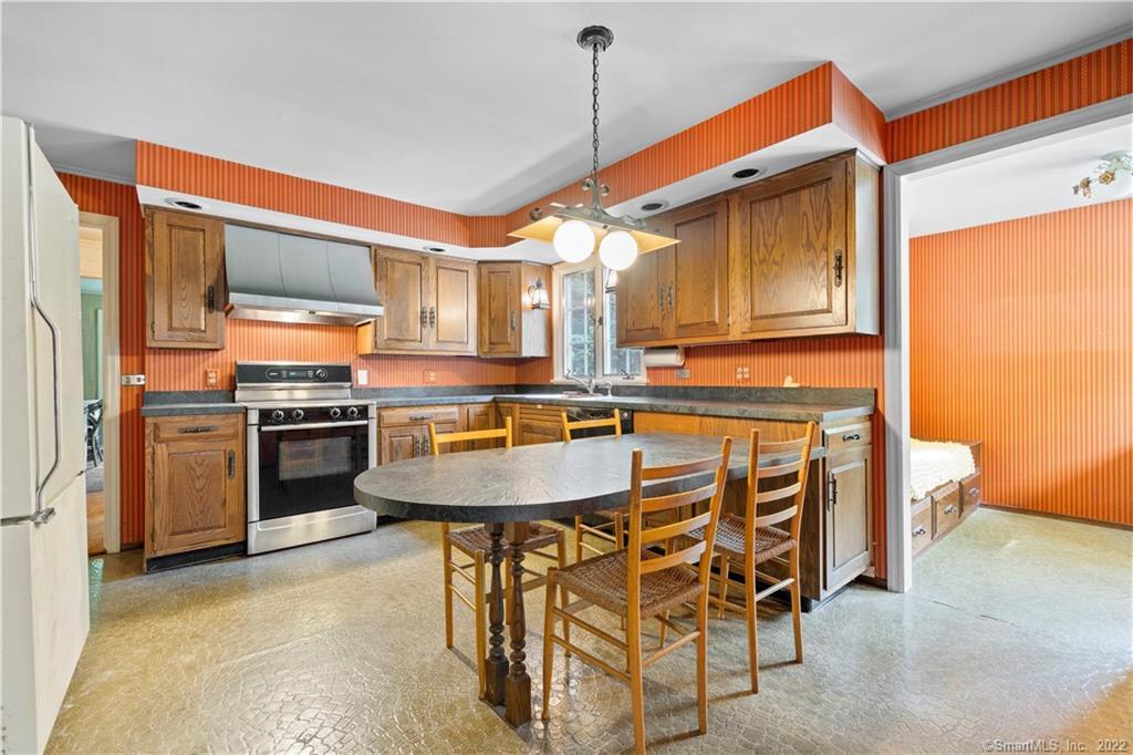 Kitchen with wood cabinets, orange striped wallpaper, and a dining table with chairs.