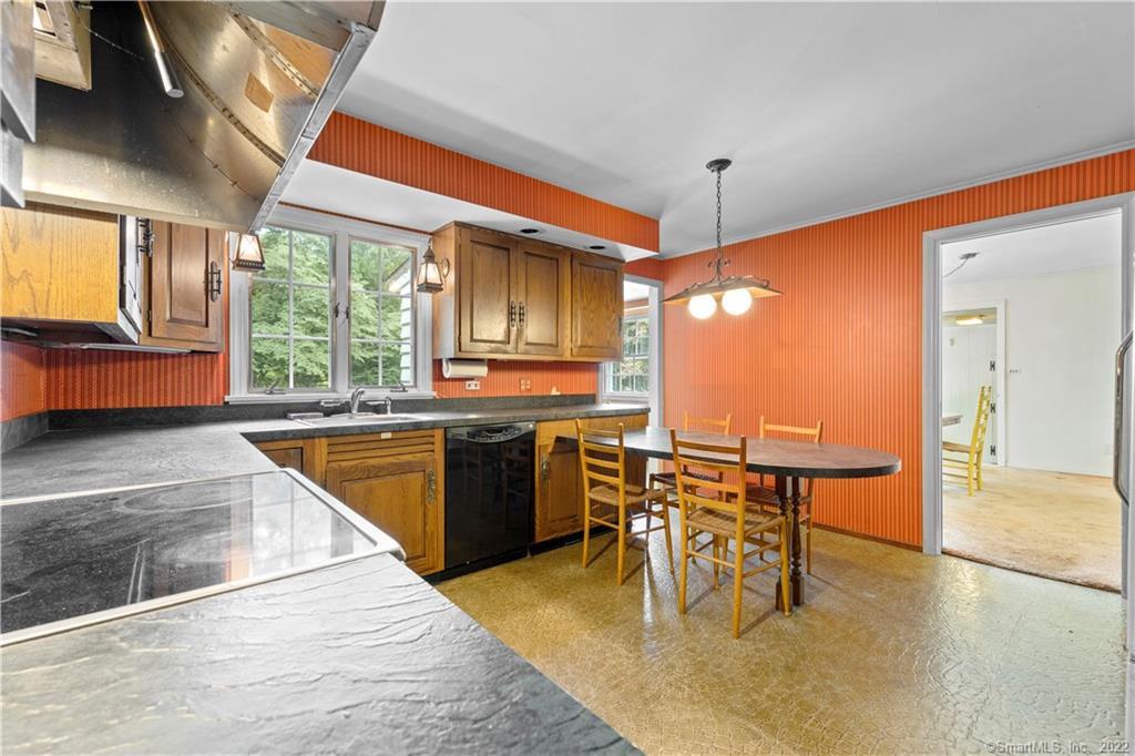 Kitchen with orange striped walls, wood cabinets, and a round dining table beside the windows.