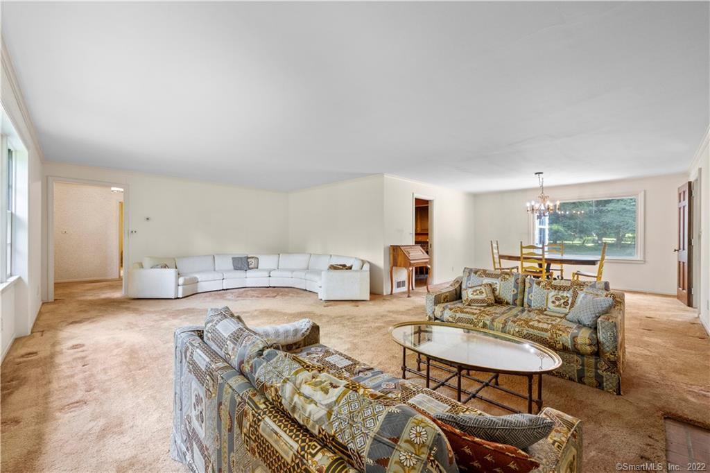 Spacious living room with a white sectional, patterned seating, and a dining area by a large window.