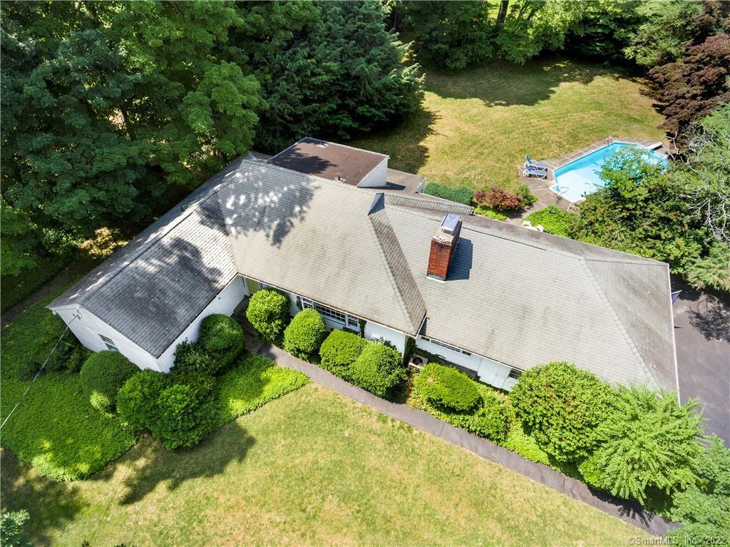 Aerial view of a single-story home with a backyard swimming pool and mature trees.
