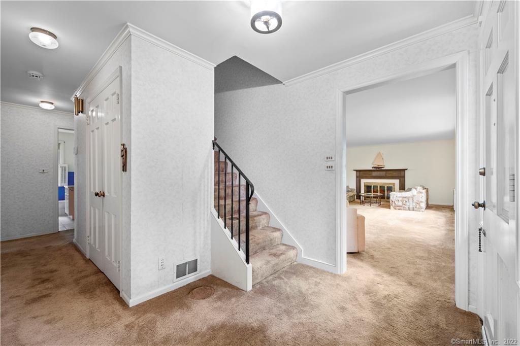 Foyer with a carpeted staircase and an open doorway to a living room with a fireplace.