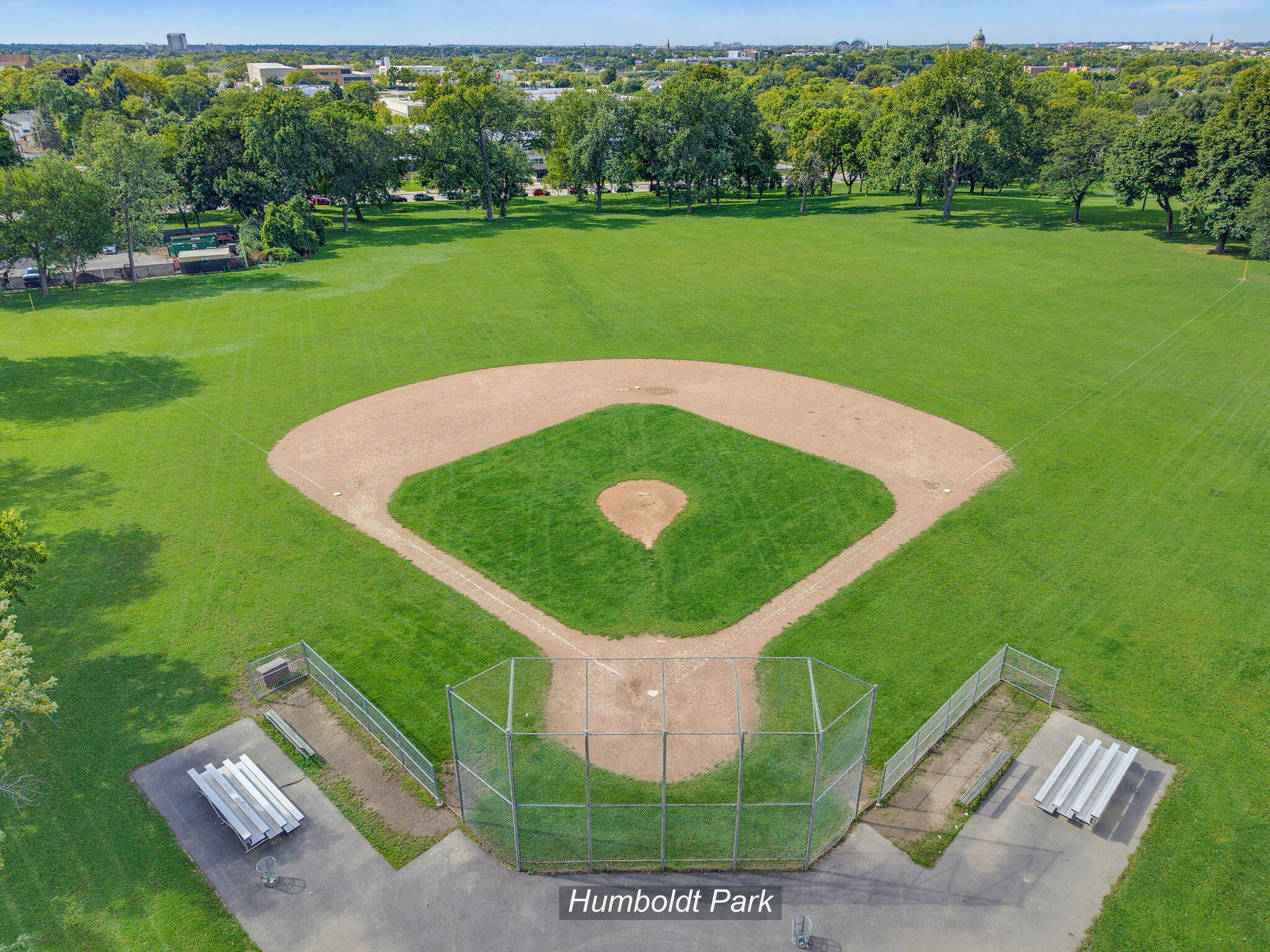 Humboldt Park baseball field with a dirt infield, chain-link backstop, and bleachers.