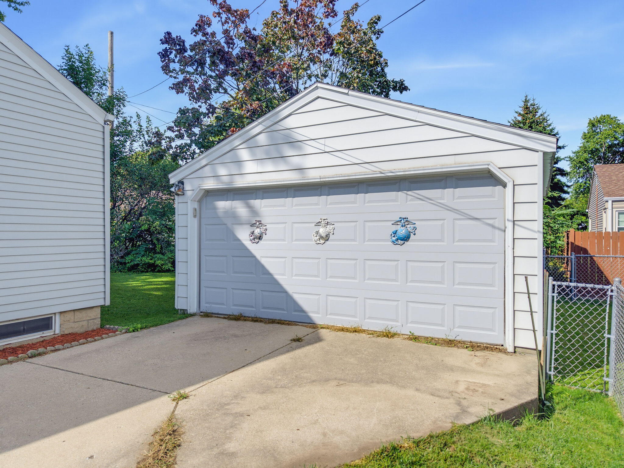 White detached garage with a double door and concrete driveway.