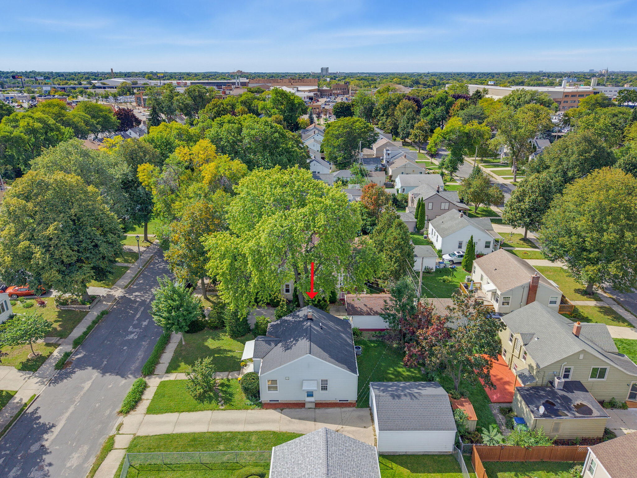 Aerial view of a tree-lined neighborhood, with a red arrow marking the property.