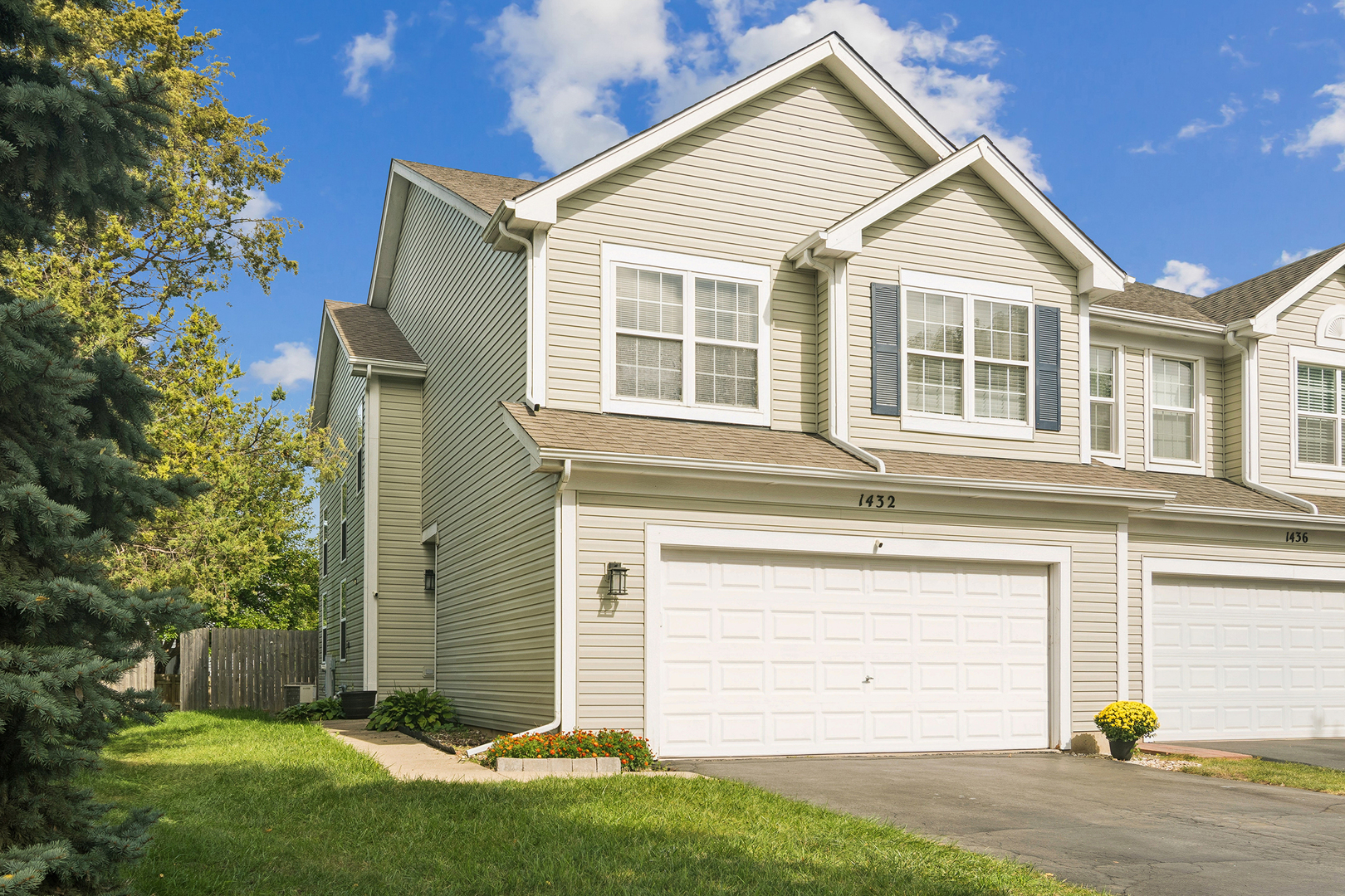 Beige two-story home at 1432 with dark shutters, a double garage, and a sunny front lawn.