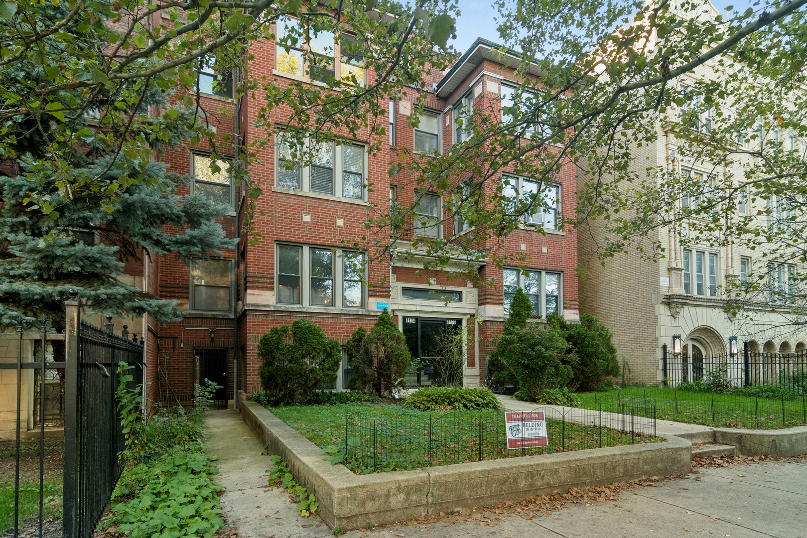Red-brick apartment building at 4134 N Keystone Avenue, framed by mature trees and a landscaped front garden.