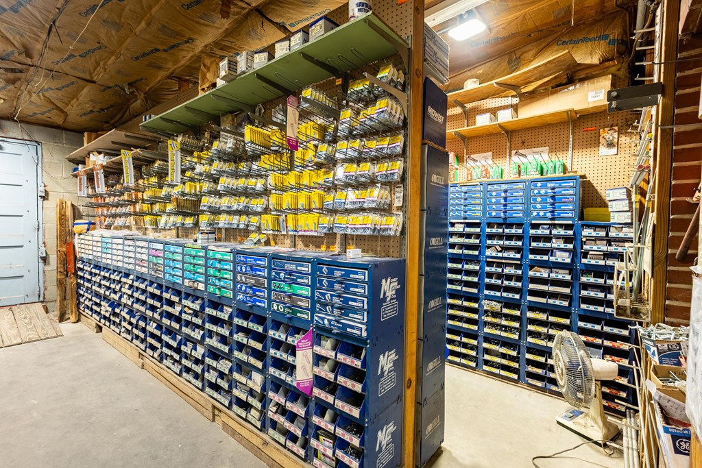 Stocked workshop with rows of blue parts bins and packaged supplies on pegboard shelves.