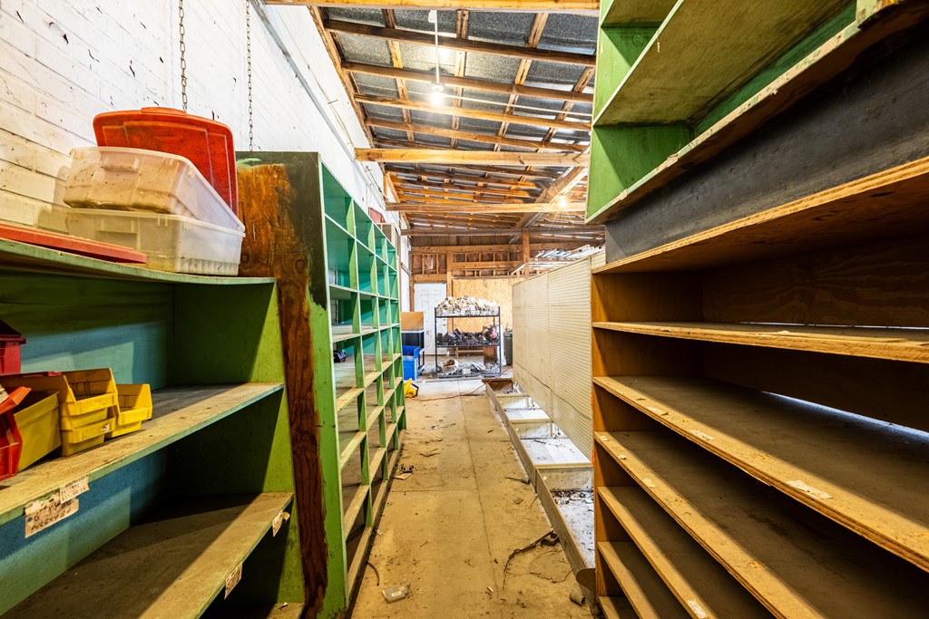 Storage room with green and wooden shelving, plastic bins, and an exposed timber ceiling.