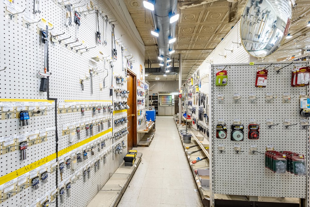 Hardware store aisle lined with stocked pegboard displays beneath a patterned ceiling.