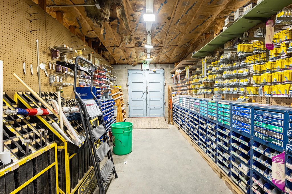Hardware store interior with tool displays, blue parts bins, and an exposed insulated ceiling.