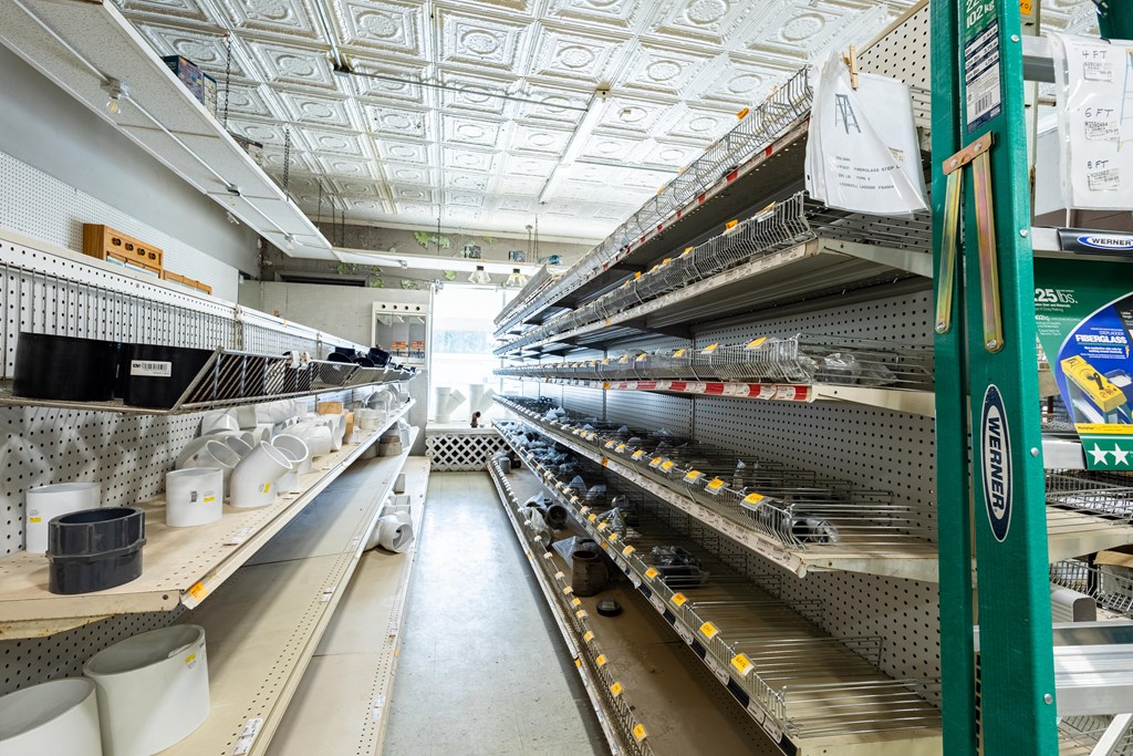 Retail store aisle with plumbing supplies, pegboard shelving, and a green Werner ladder.