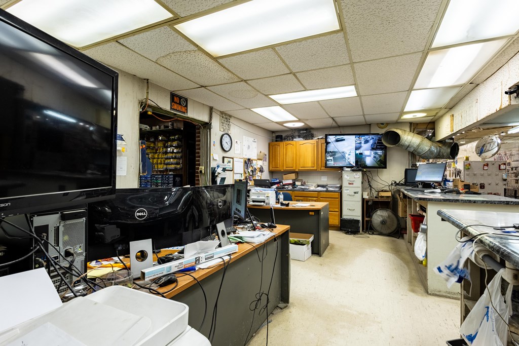 Office workroom with computer monitors, security screens, and crowded desks.