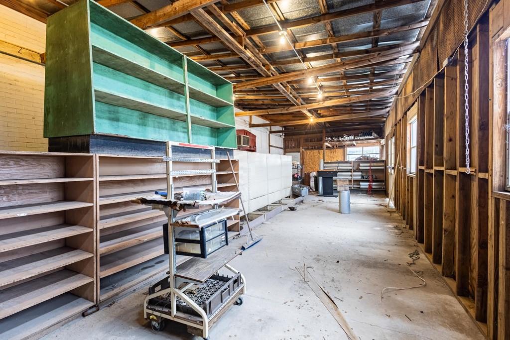 Workshop interior with green shelving, exposed ceiling beams, and rolling work carts.