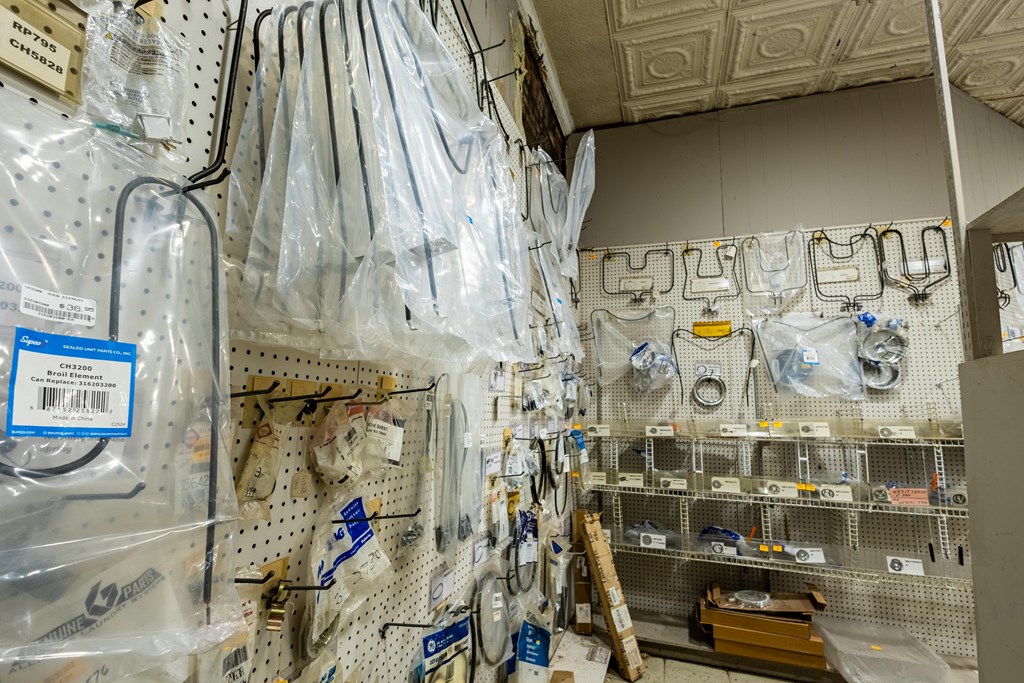 Shop interior with packaged appliance parts hanging on pegboard walls and displayed on shelves.