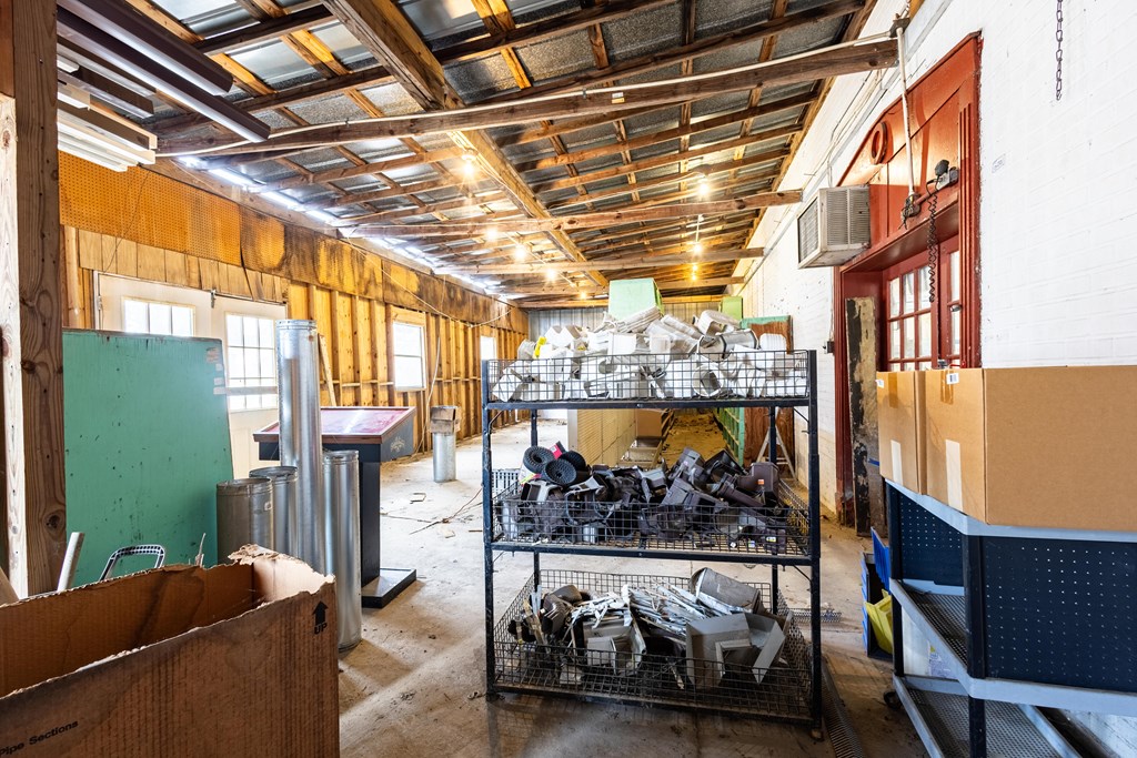 Workshop interior with exposed roof framing, storage carts, and assorted equipment.