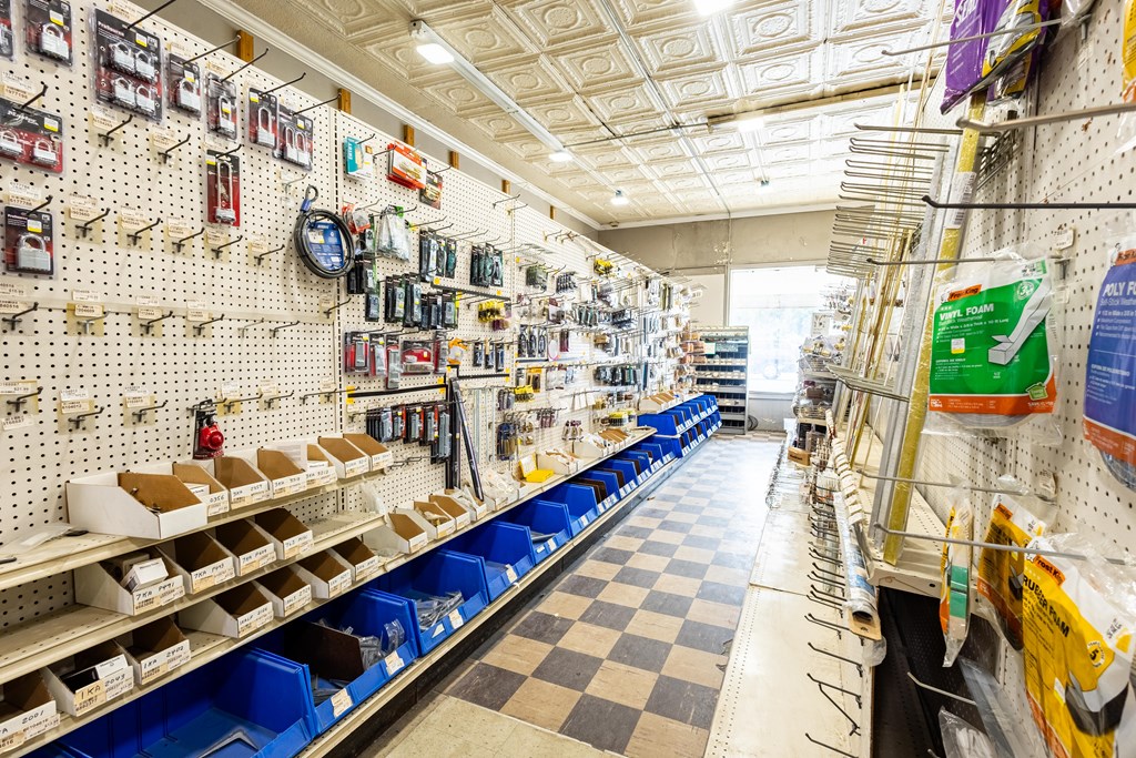Hardware store interior with stocked pegboard shelves, blue parts bins, and a checkerboard floor.