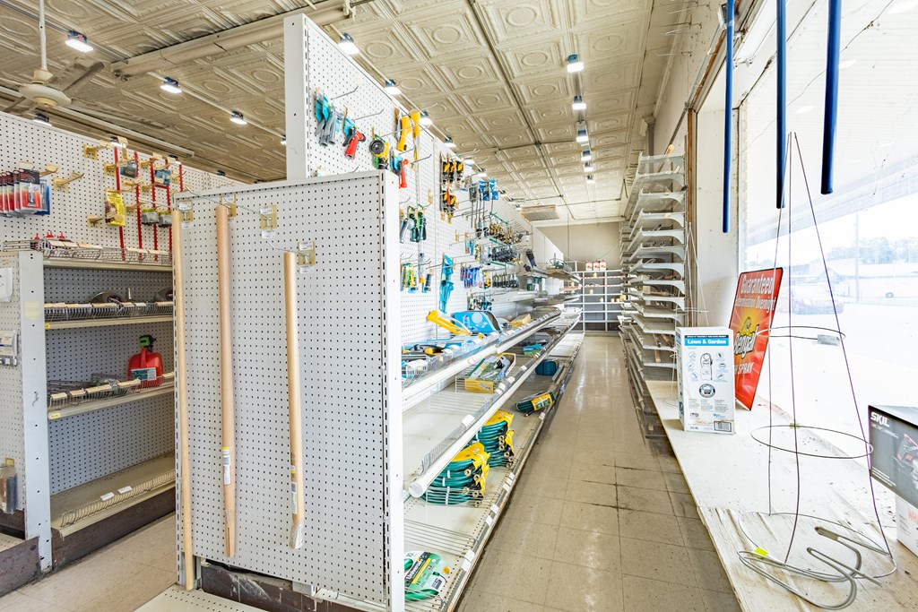 Hardware store interior with tool displays, garden supplies, and large front windows.