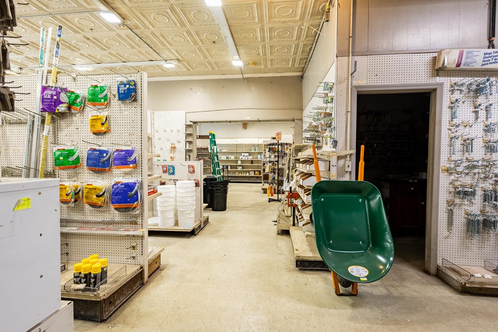 Retail store interior with stocked pegboard displays and a green wheelbarrow in the aisle.