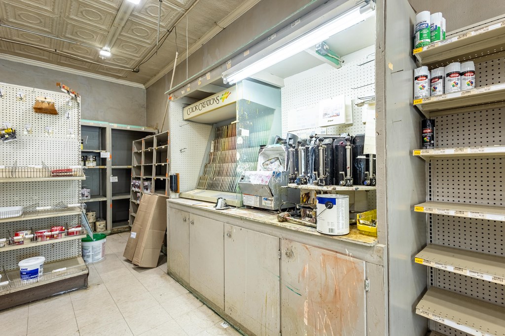 Retail shop interior with paint-mixing equipment, a service counter, and mostly empty display shelves.