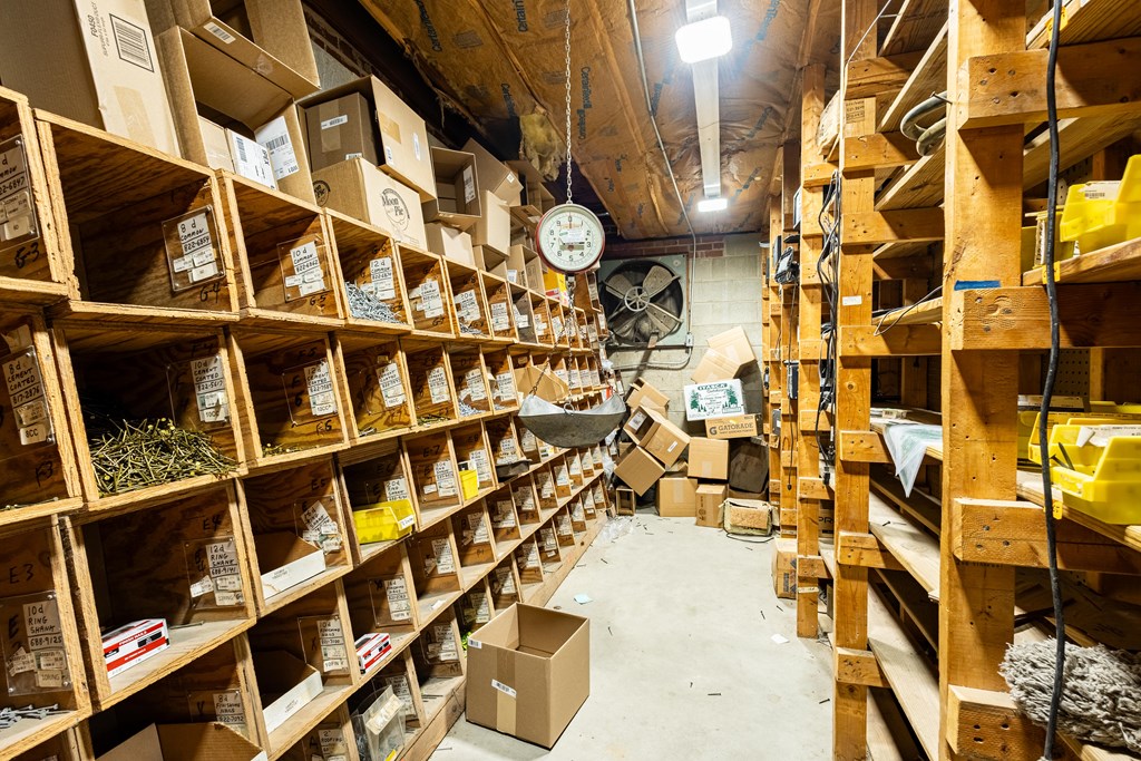 Storage room with wooden supply shelves, crowded boxes, and an open aisle.
