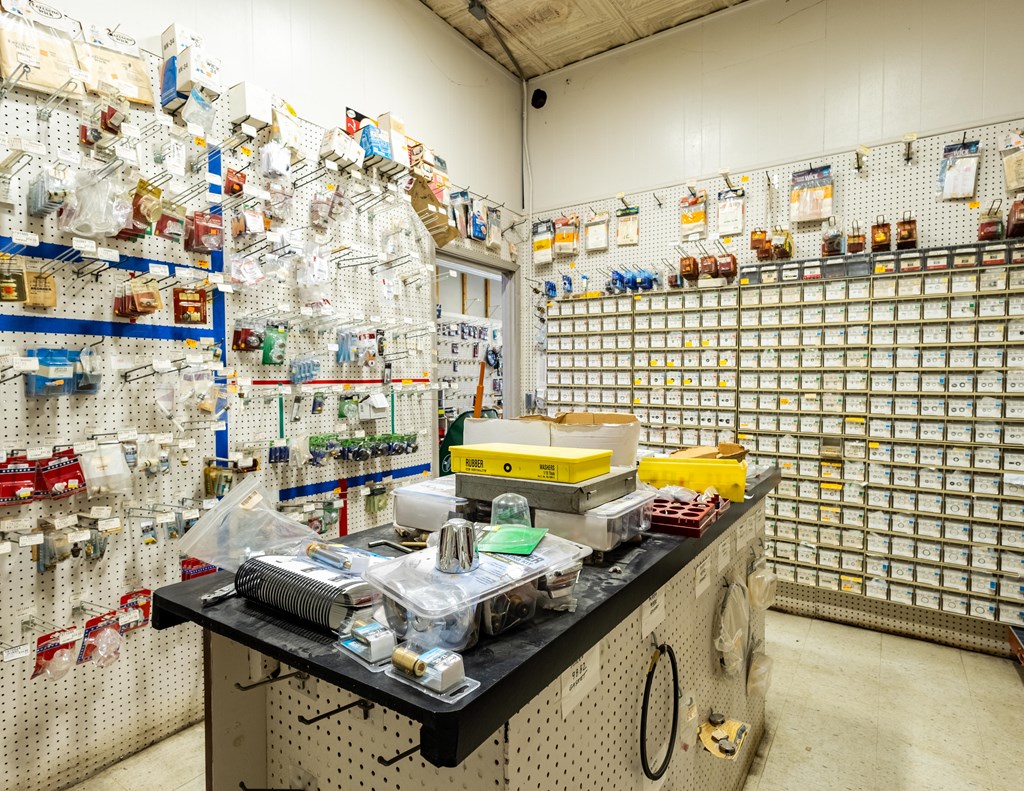 Retail shop interior with stocked pegboard walls and a central counter covered in supplies.